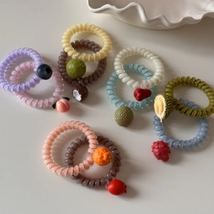 Vue détaillée d'élastiques spirales à motifs de fruits colorés avec breloques