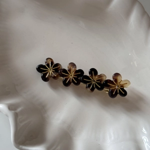 Détail d'une barrette à fleurs en résine ambrée avec pistils dorés sur une coupelle blanche