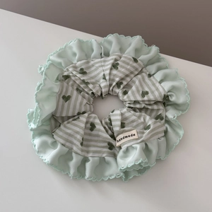Detail of mint green ruffled edge and striped heart pattern on handmade fabric hair scrunchie