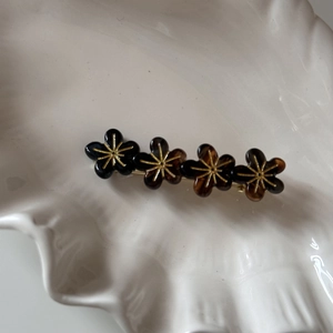 Détail de la pince à cheveux à fleurs en résine écaille sur un plateau coquillage