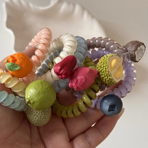 Main tenant divers élastiques spirale avec motifs de fruits comme citron et orange