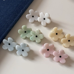 Five pairs of macaron-colored flower hair claws in pastel tones on a cream backdrop