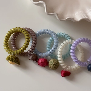 Ensemble d'élastiques spirales avec breloques de fruits colorés sur fond blanc