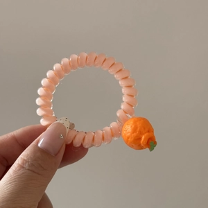Détail de l'élastique spirale rose avec un petit pendentif en résine en forme d'orange