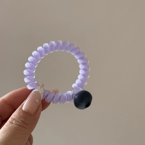 Vue détaillée d'un élastique spirale violet avec breloque myrtille à la main