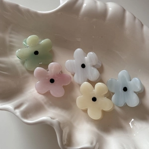 Set of five small floral hair clips in macaron colors on a seashell ceramic tray