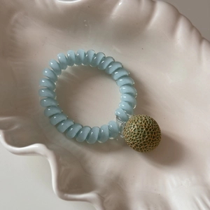 Détail de l'élastique spirale bleu clair avec un pendentif réaliste en forme de melon