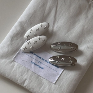 Detail of four-piece hair clip set featuring silver and white bow relief decorations