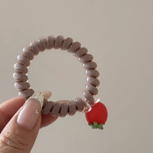 Détail d'un élastique à cheveux en fil de téléphone avec pendentif tomate cerise rouge