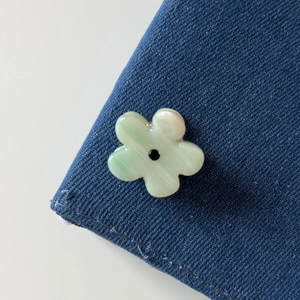 Detailed view of a light green flower hair clip with rhinestones on denim fabric