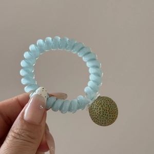 Gros plan d'un élastique spirale bleu avec un pendentif melon vert détaillé