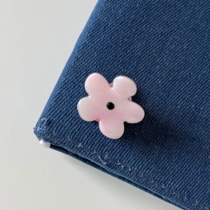 Close-up of pink flower hair clip with center gem on denim fabric background