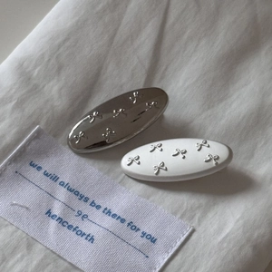 Minimalist silver and matte white oval hair clips with 3D bow patterns for women