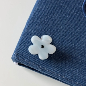 Detailed view of denim fabric texture featuring a blue and white flower embellishment