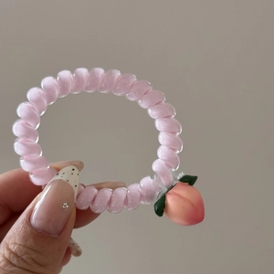 Vue détaillée d'un élastique spirale rose avec un pendentif pêche en 3D et des feuilles