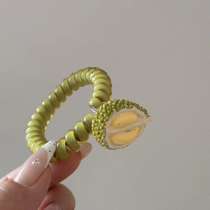 Détail d'un élastique spirale vert orné d'un élément réaliste de fruit durian jaune