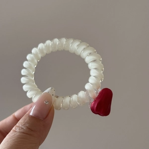 Gros plan d'un élastique spirale blanc avec un petit cœur rouge mat tenu en main