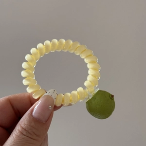 Gros plan d'un élastique spirale jaune avec un petit pendentif en forme de fruit