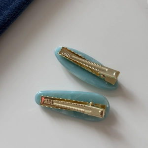 Detail of blue acetate hair clips with marble texture and gold metal duckbill clips