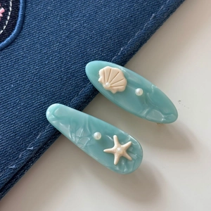 Close-up of blue ocean-themed hair clips with starfish, shell and pearl accents