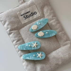 Close-up of ocean-themed hair clips with blue marble texture, shells, and starfish