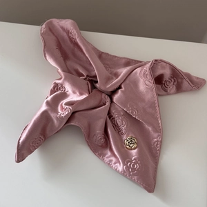 Detail view of pink satin scrunchie with rose jacquard fabric and a gold floral button