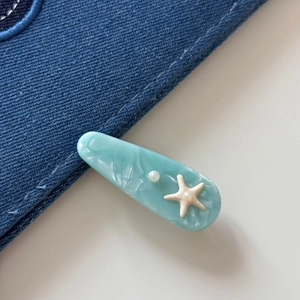 Detail of sea blue starfish acetate hair clip with marble texture and pearl accent