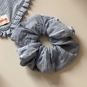 Gros plan du chouchou bleu clair avec nœuds brodés sur tissu en mousseline plissée