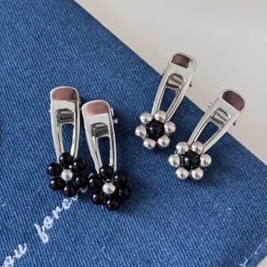 Set of four silver metal flower duckbill hair clips on blue denim background