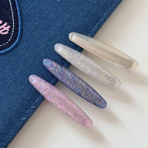 Glittery cat-eye oval hair clips in pink and purple colors on denim background