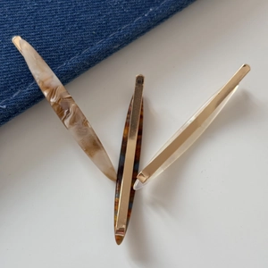 Detailed view of three acrylic hair clips in marble and tortoiseshell on denim background