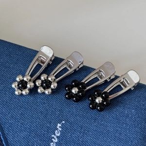Set of four silver metal flower hair clips with black beads on denim background