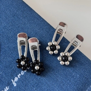 Close-up of four floral hair clips with black and silver bead petals on denim fabric