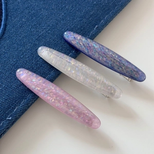 Three-piece oval glitter hair clips set in pink, white, and blue resin on denim
