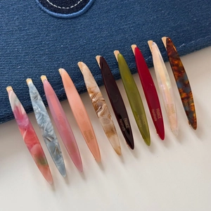 Close-up of slender willow leaf hair clips in ten assorted colors on denim background