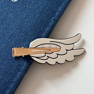 Close-up of silver wing hair clip with rhinestones on a blue denim background