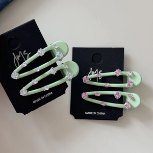 Macro-opname van muntgroene strass-haarspelden met roze stenen op presentatiekaarten