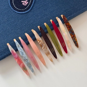 Macro detail of assorted handmade acetate hair clips with golden metal clips and textures