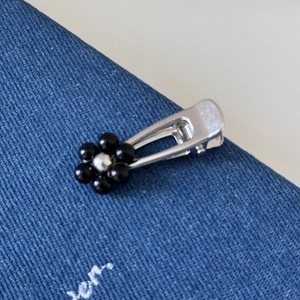 Close-up of a silver flower hair clip with black beads on dark blue fabric background