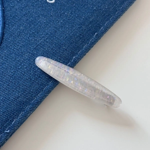 Macro view of shell cat eye hair clip showing sparkling iridescent glitter in resin