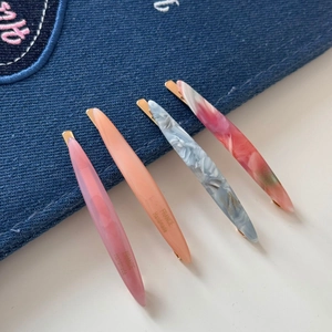 Detailed close-up of four slender acetate leaf-shaped hair clips with marble texture
