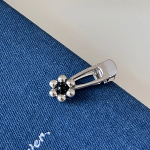 Detailed macro of silver metal flower hair clip with black bead center on denim fabric