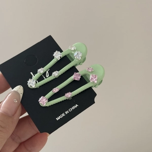 Detail van muntgroene haarspeldjes met roze strass-steentjes op een presentatiekaart