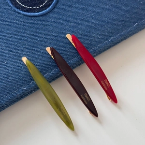 Close-up of slender willow leaf hair clips in olive, burgundy and red resin