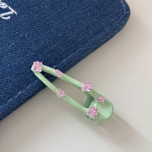 Detailopname van de muntgroene haarklem met fonkelende roze kristallen op denim