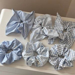 Detailed close-up of blue striped scrunchies with elegant bow embroidery and woven labels