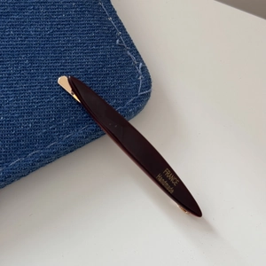 Detailed close-up of a handmade dark red acetate hair clip with gold metal spring base