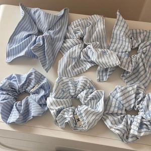 Detailed embroidery of a blue bow on striped fabric hair scrunchie and hair ribbon