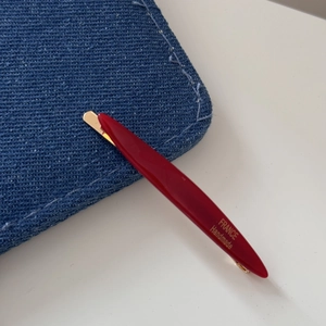 Close-up of red resin hair clip with gold metal base and FRANCE Handmade text