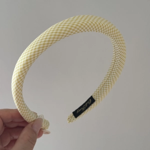 Detail showing the thick sponge padded yellow and white plaid headband with brand label
